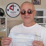 Image of man (Bruce) holding donation check for Victory Kitchen