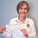 Photo of Sue holding donation check for Serving Our Seniors